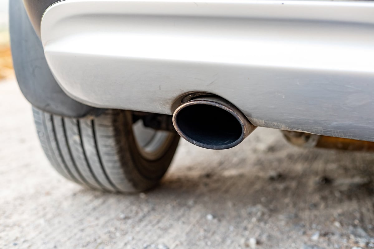 Close-up of a vehicle exhaust pipe during an emissions test at an auto repair shop.