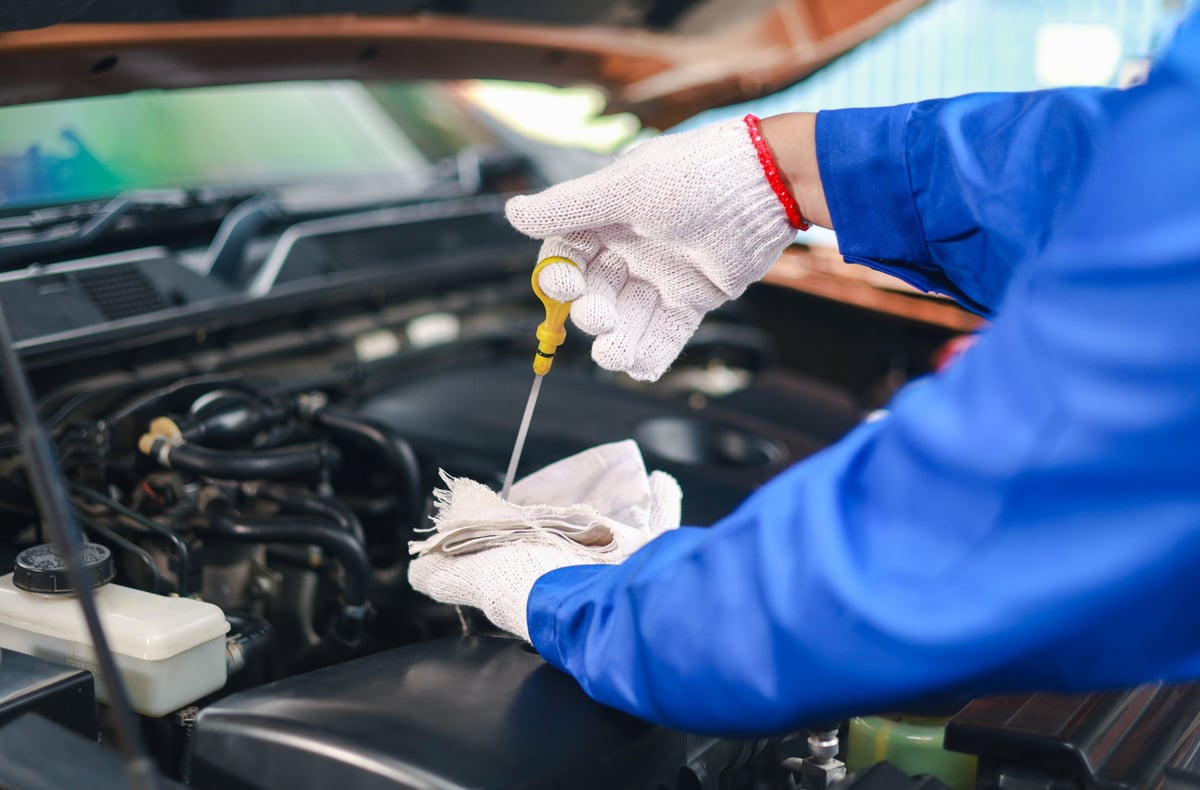Close-up of a car mechanic checking the engine oil. Inspect and maintain the car engine to ensure it is in perfect working order.