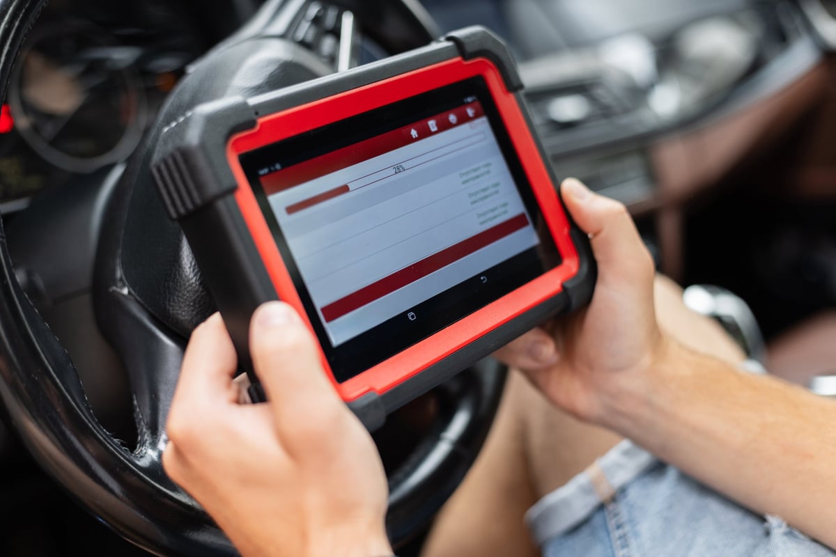 Mechanic using a digital diagnostic scanner to check car systems inside the vehicle.