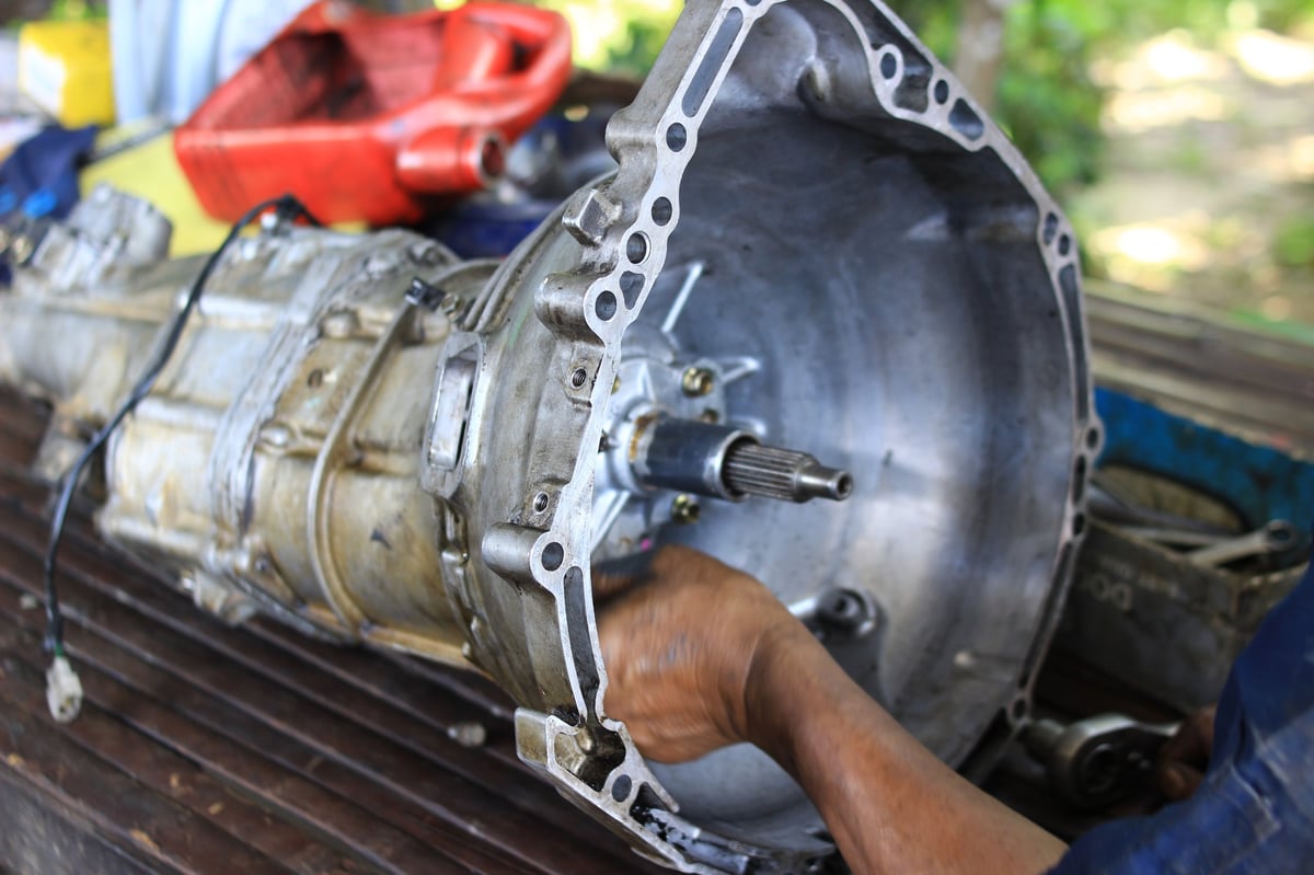 The hands of a mechanic repairing a car transmission.