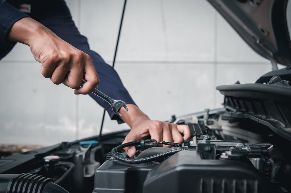 Mechanic working on car engine with diagnostic tools
