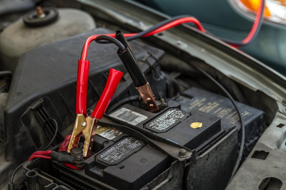 Car battery with jumper cables giving a load to another car battery during an emergency jump start.