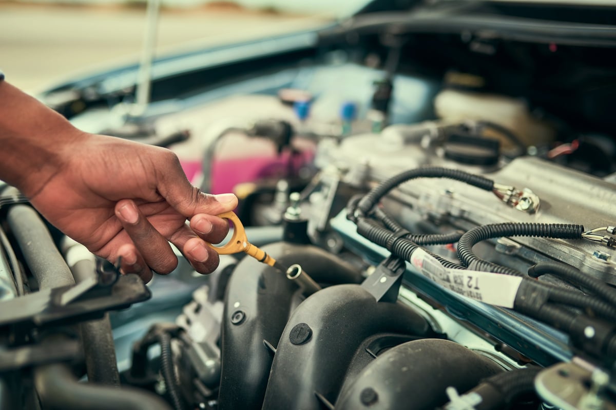 Cropped shot of a young man checking his engine oil after breaking down